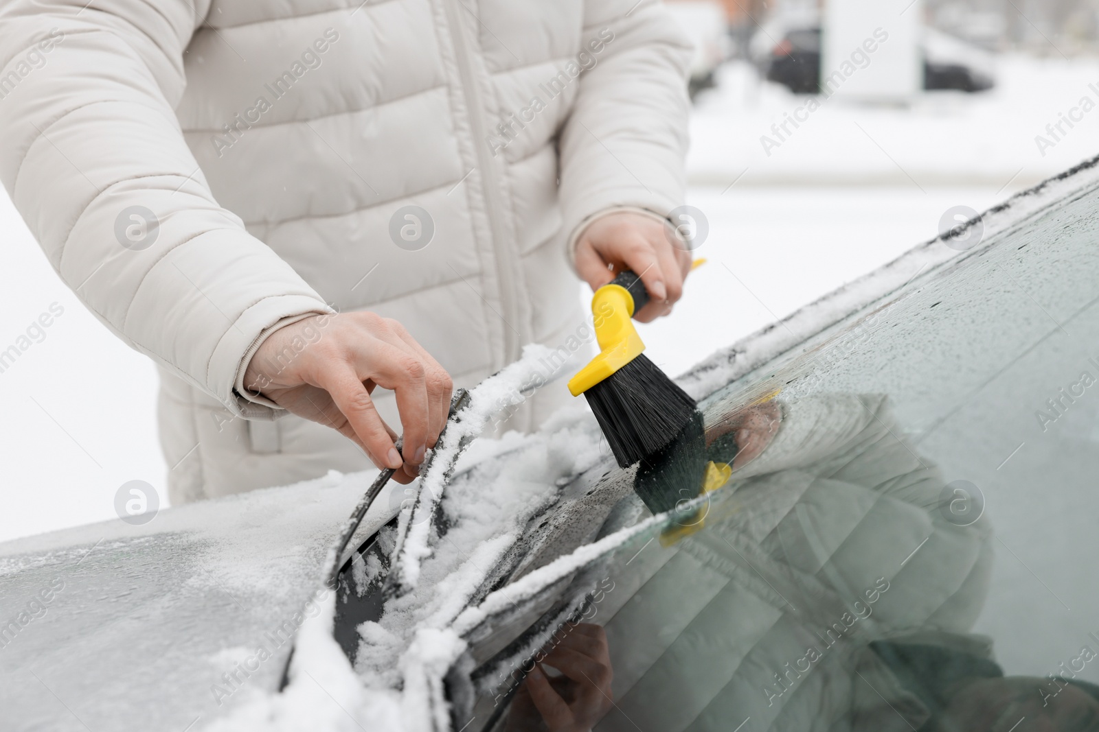 Photo of Man cleaning snow from car windshield outdoors, closeup