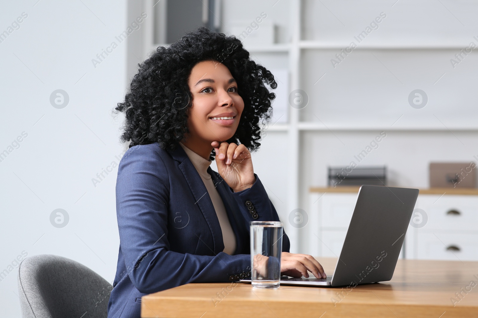 Photo of Young woman working on laptop at table in office