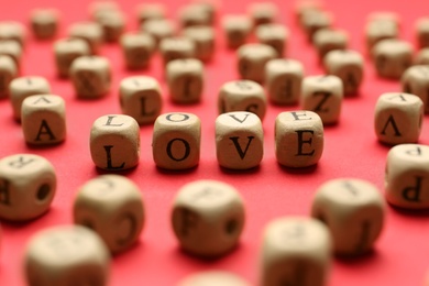 Photo of Mini cubes with letters forming word Love on red background, closeup