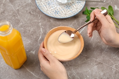 Photo of Woman with vanilla pudding at table, closeup