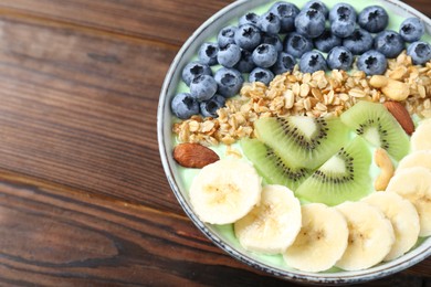 Photo of Tasty smoothie bowl with fresh fruits and oatmeal on wooden table, closeup. Space for text