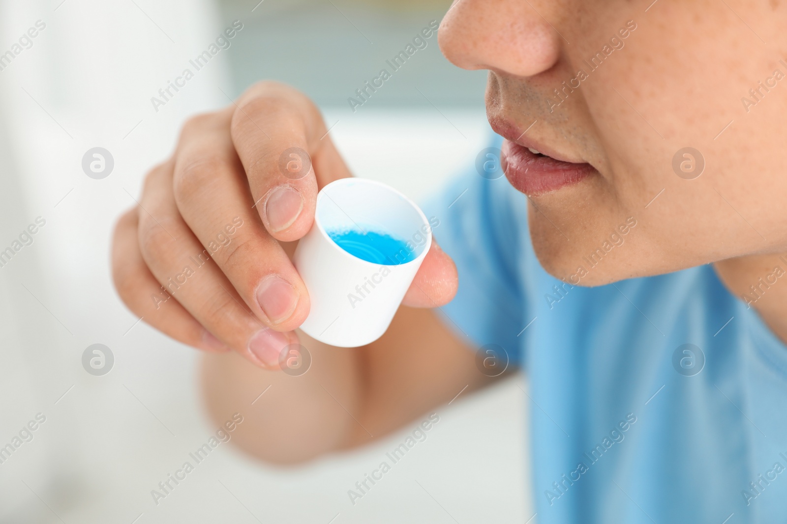 Photo of Man holding cap with mouthwash, closeup view. Teeth care