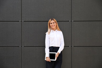 Photo of Female real estate agent with blank tablet near dark wall