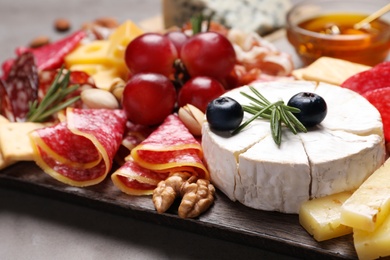 Wooden board with different appetizers on table, closeup