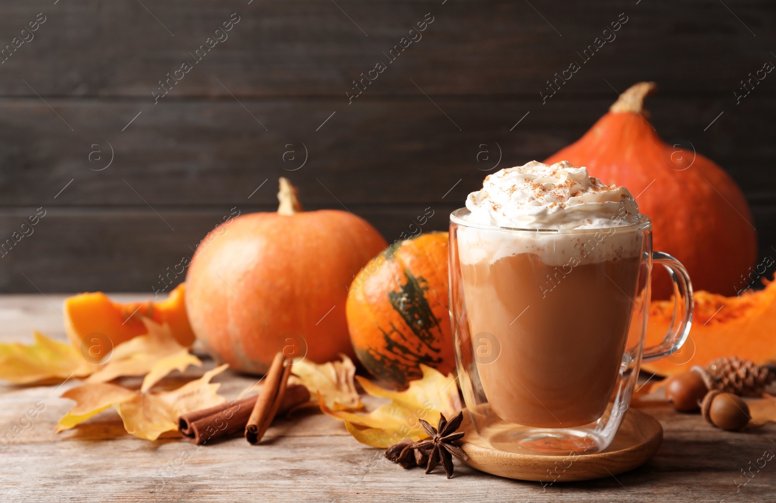 Photo of Glass cup with tasty pumpkin spice latte on wooden table