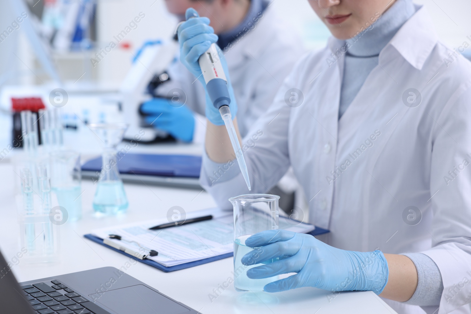 Photo of Scientist dripping sample into beaker in laboratory, closeup