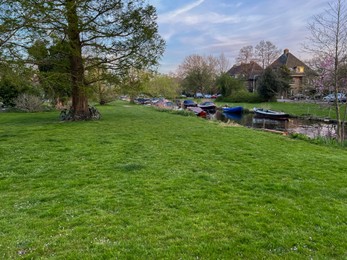 Beautiful view of canal with different boats near green lawn