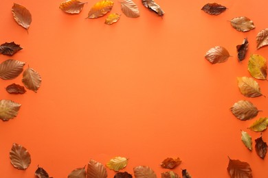 Frame of autumn leaves on orange background, flat lay. Space for text