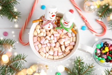Image of Flat lay composition with marshmallow snowmen in cup of hot drink on white wooden table. Bokeh effect 