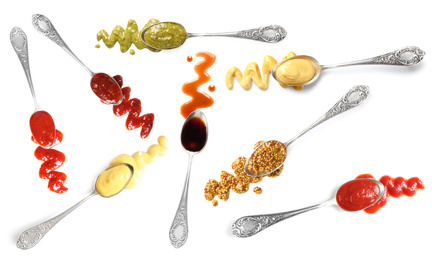 Set of spoons with different delicious sauces on white background, top view