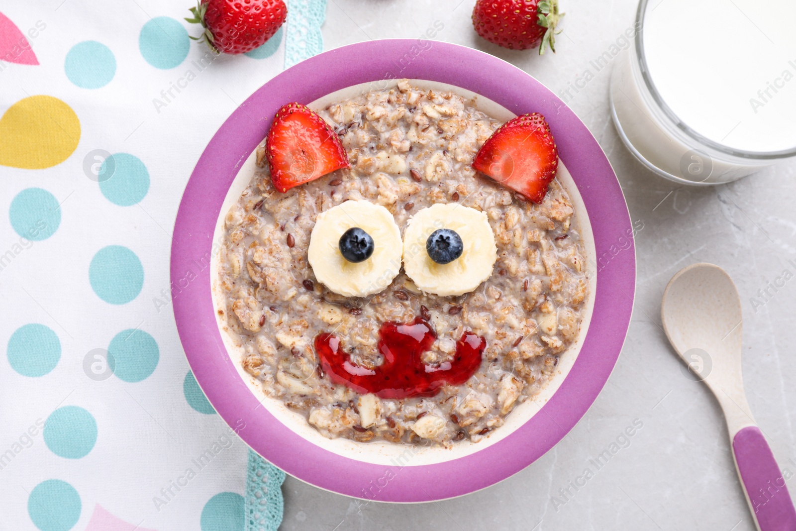 Photo of Tasty porridge served with berries, jam and milk on marble table, flat lay. Creative idea for kids breakfast