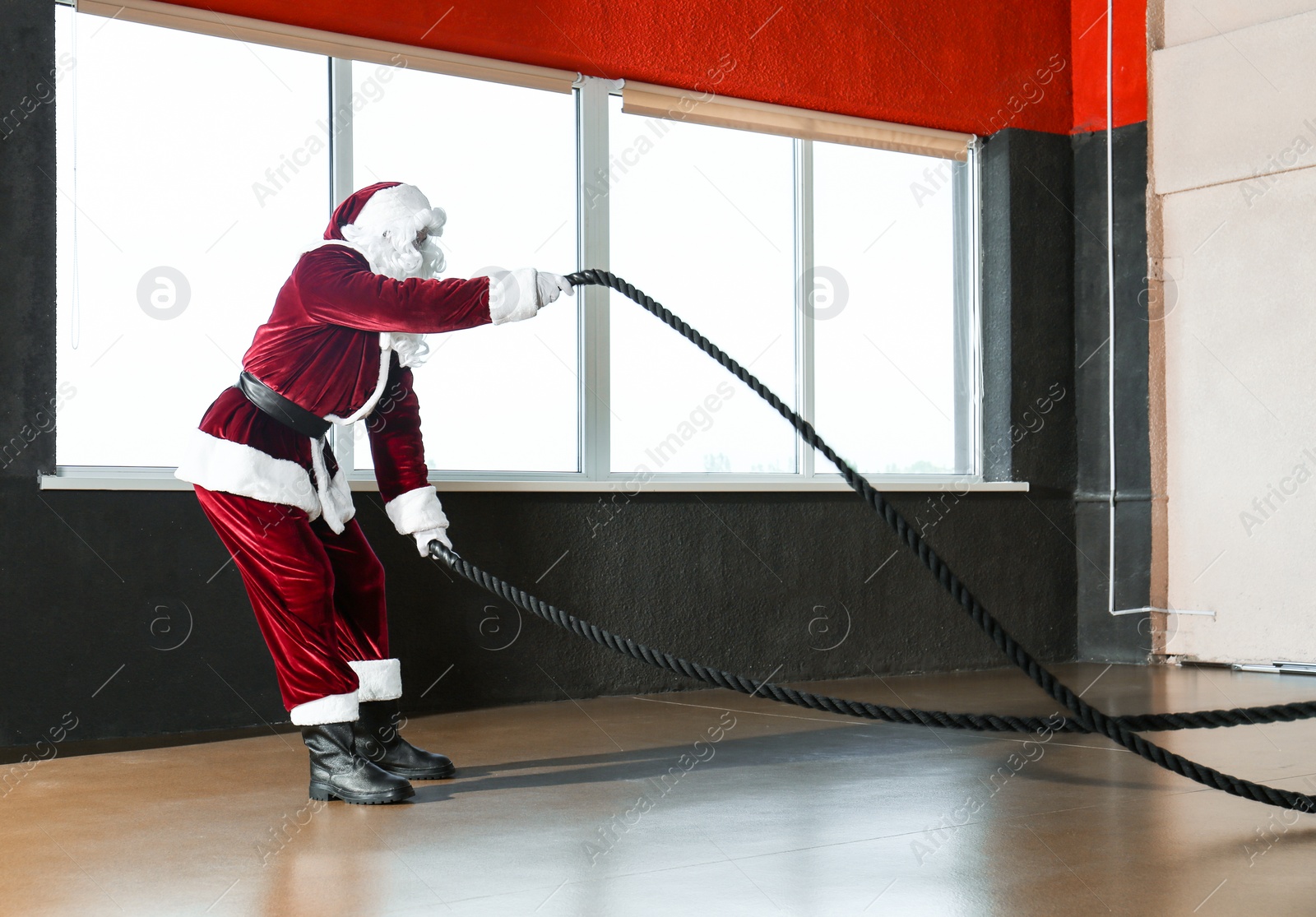 Photo of Young Santa Claus training with ropes in modern gym