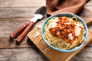 Photo of Bowl with delicious pasta bolognese on wooden table