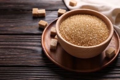 Brown sugar in bowl on wooden table. Space for text