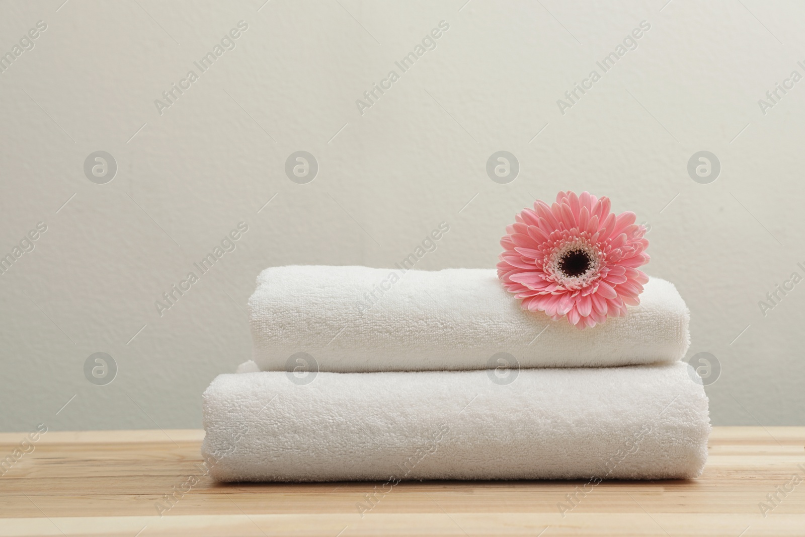 Photo of Stack of fresh towels with flower on table. Space for text