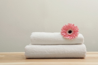 Stack of fresh towels with flower on table. Space for text