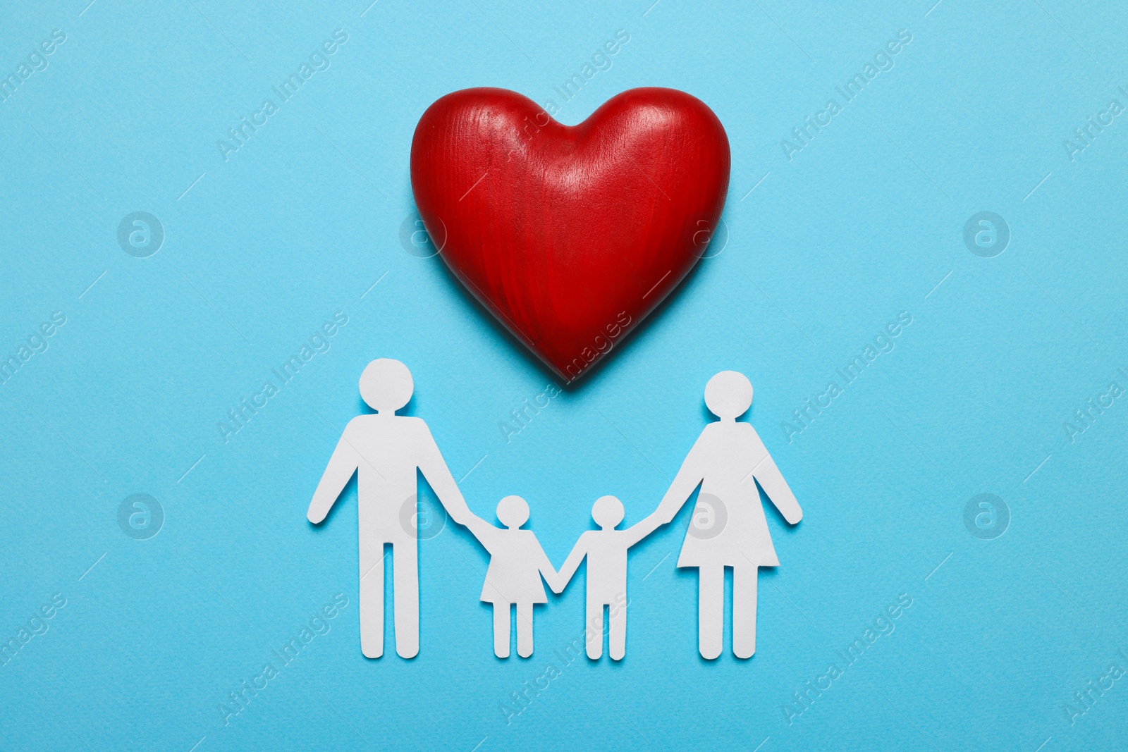 Photo of Paper family figures and red wooden heart on light blue background, flat lay. Insurance concept