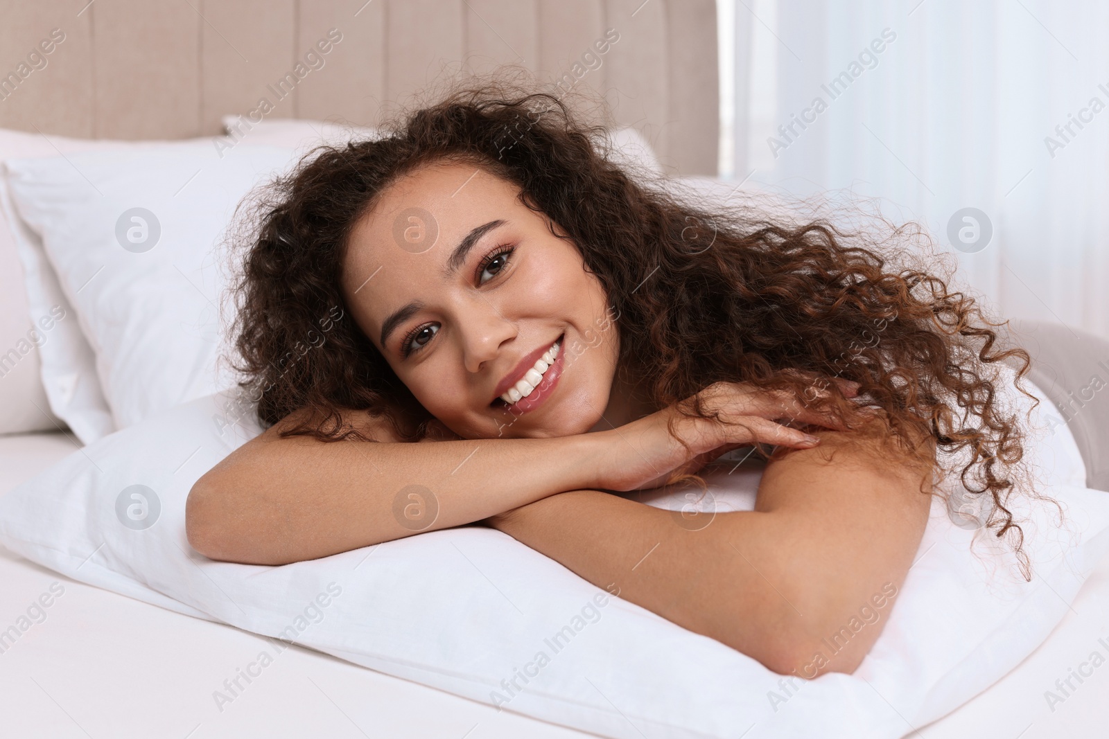 Photo of Happy African American woman lying on bed at home