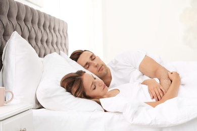 Photo of Young couple sleeping on soft pillows in bed at home