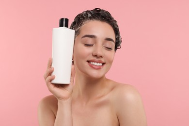 Photo of Washing hair. Portrait of beautiful happy woman with bottle on pink background