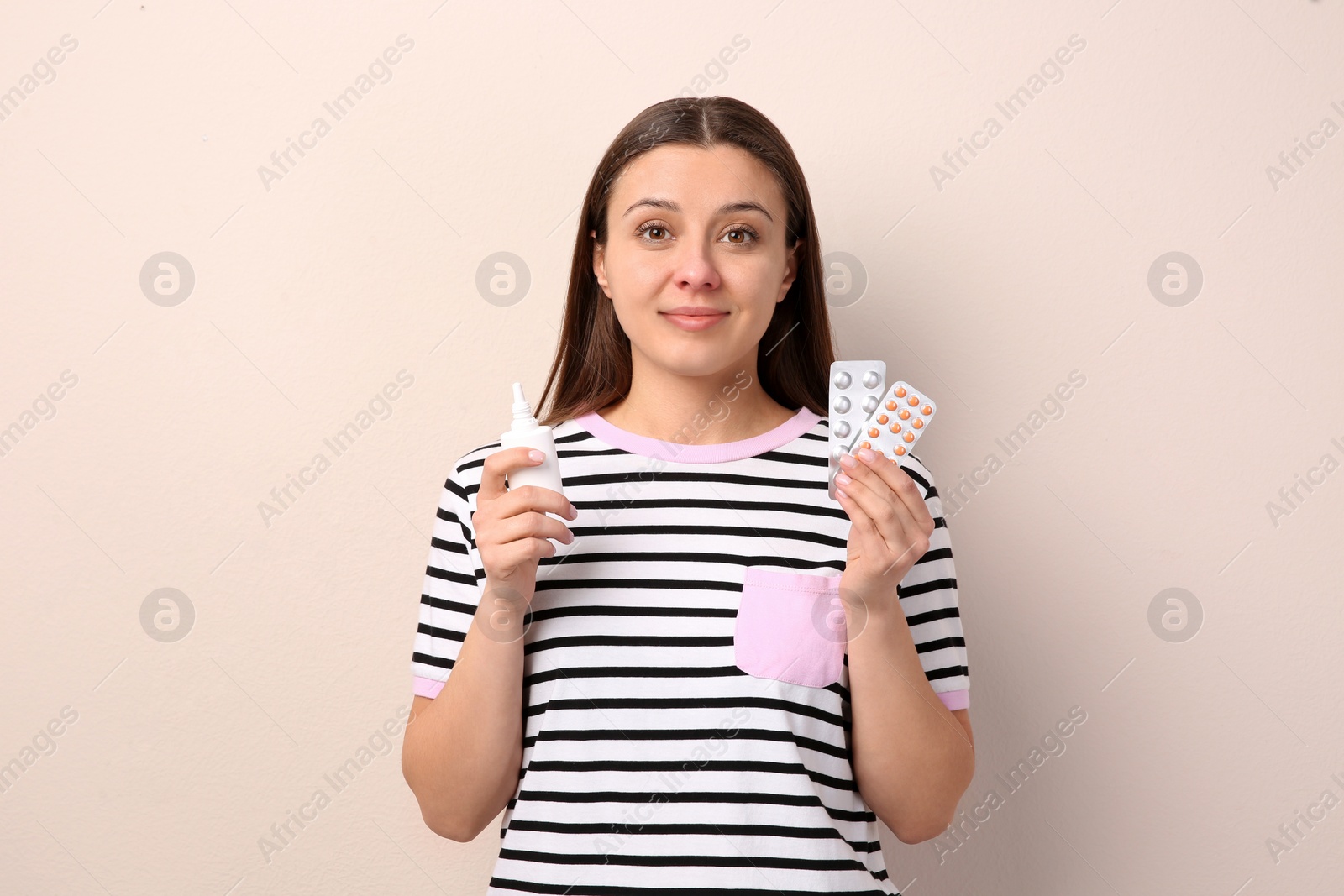 Photo of Woman with nasal spray and pills on beige background