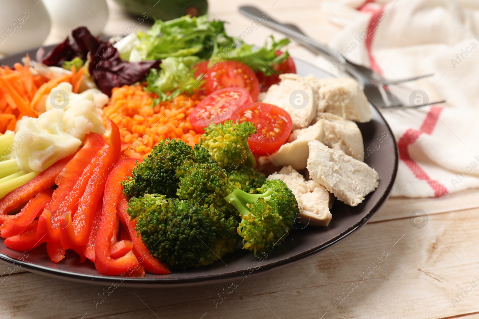 Photo of Balanced diet and healthy foods. Plate with different delicious products on light wooden table, closeup