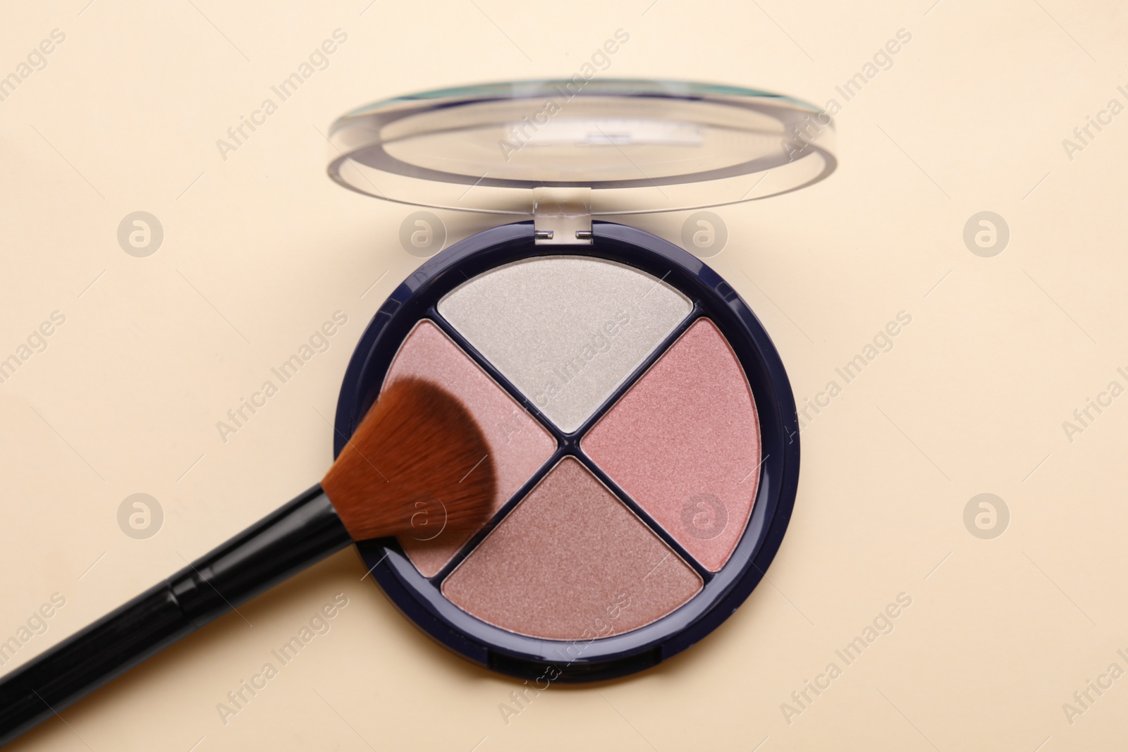 Photo of Colorful contouring palette with brush on beige background, top view. Professional cosmetic product