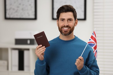 Immigration. Happy man with passport and flag of United Kingdom indoors