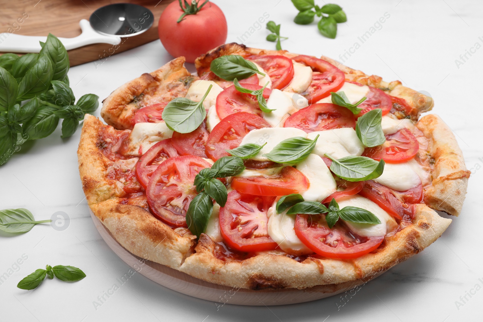 Photo of Delicious Caprese pizza with tomatoes, mozzarella and basil on white marble table, closeup