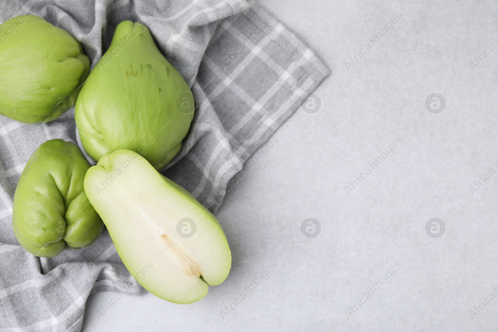 Photo of Cut and whole chayote on gray table, top view. Space for text