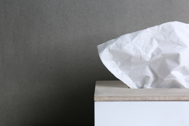 Photo of Holder with paper tissues on grey background, closeup. Space for text