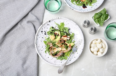 Photo of Plate of salad with melon slices and prosciutto on gray table, flat lay