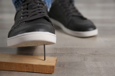 Careless man stepping on nail in wooden plank, closeup