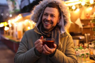 Happy man with mulled wine at winter fair