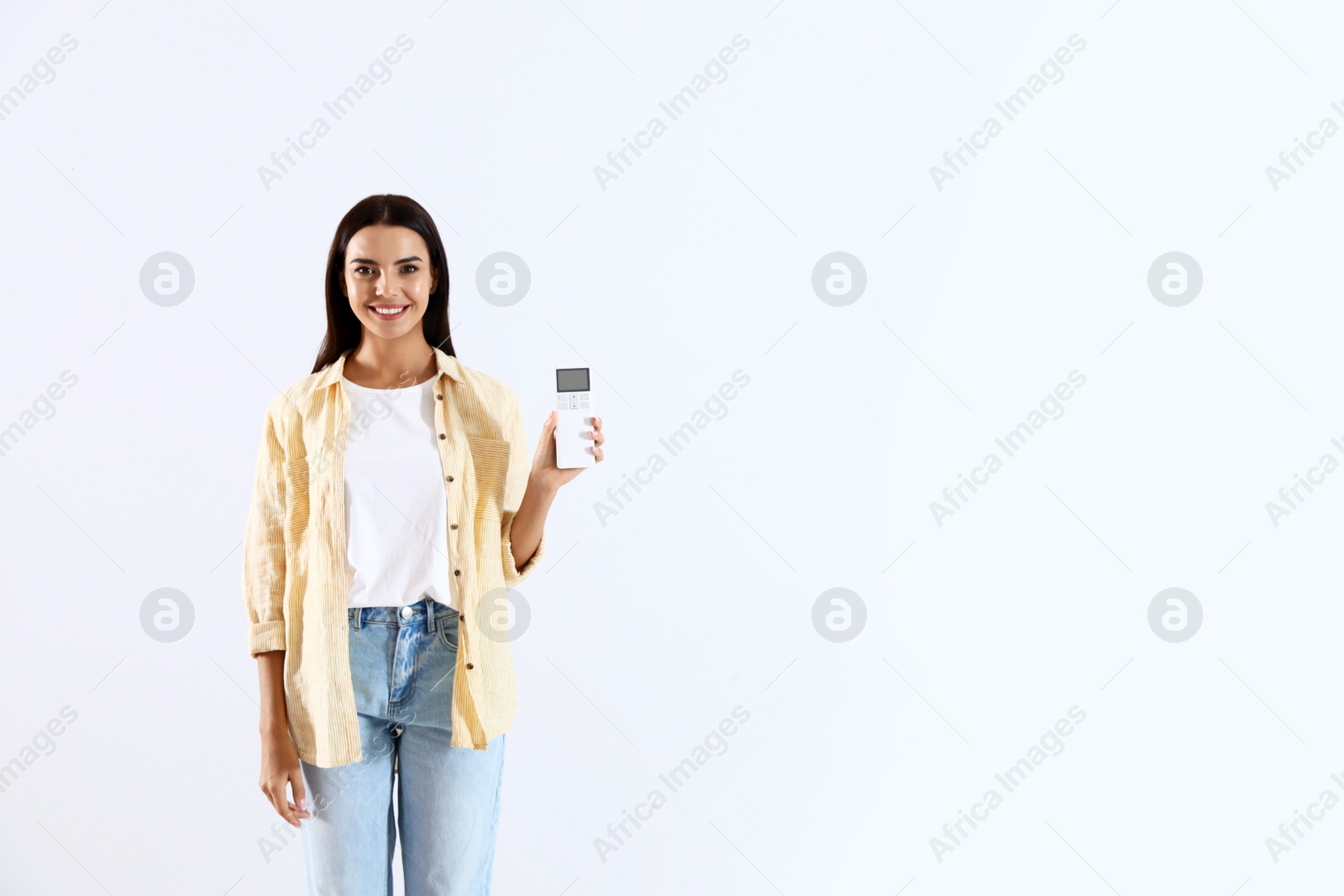 Photo of Young woman with air conditioner remote on white background