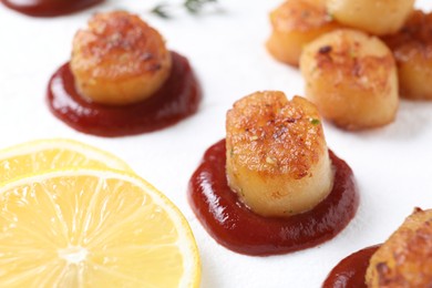 Delicious fried scallops with tomato sauce and lemon on plate, closeup