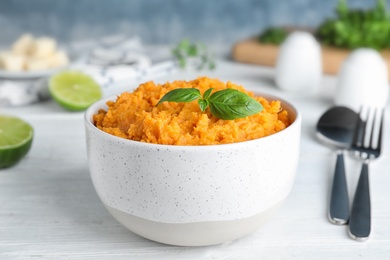 Photo of Bowl with mashed sweet potatoes on wooden table against color background