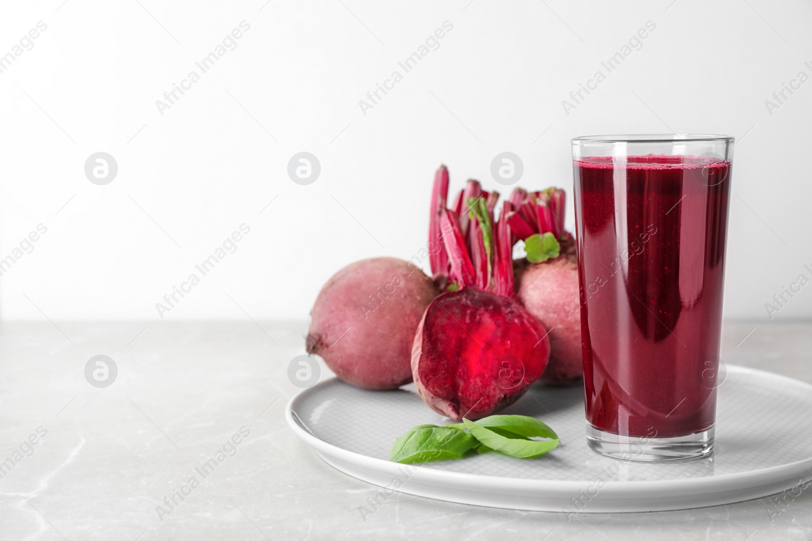 Photo of Glass of fresh beet juice, basil and vegetable on table