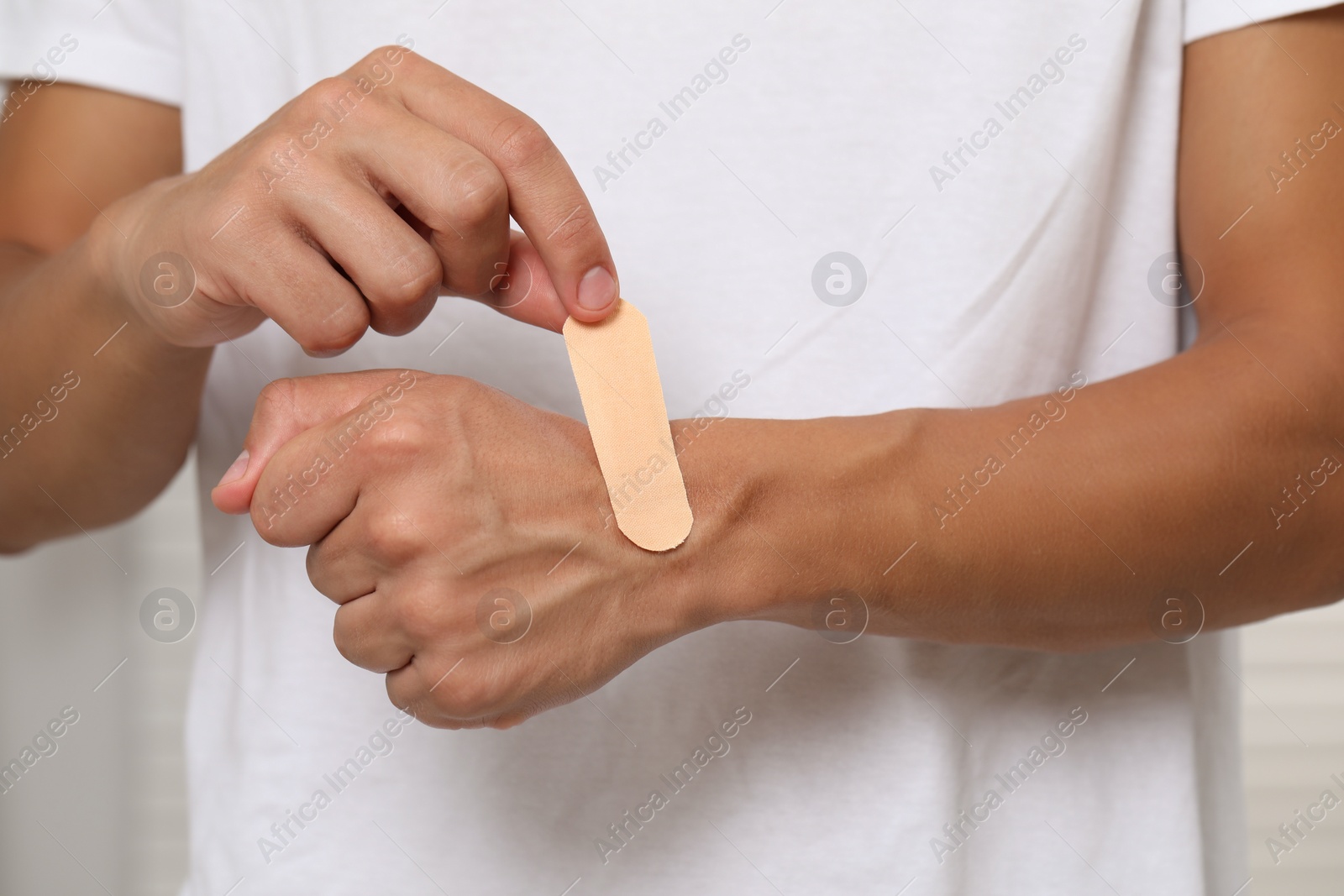 Photo of Man putting sticking plaster onto hand, closeup