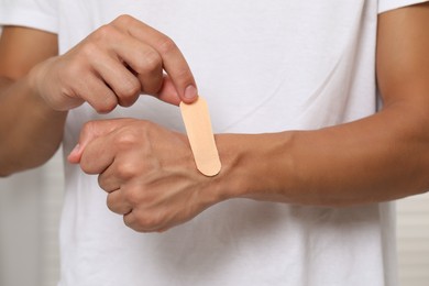 Man putting sticking plaster onto hand, closeup