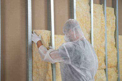 Photo of Worker in uniform insulating wall indoors, back view