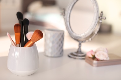 Holder with makeup brushes on table