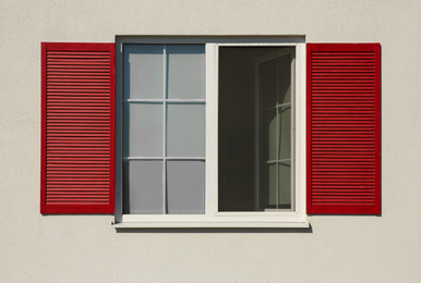 Photo of Wall of light building with beautiful window and red shutters