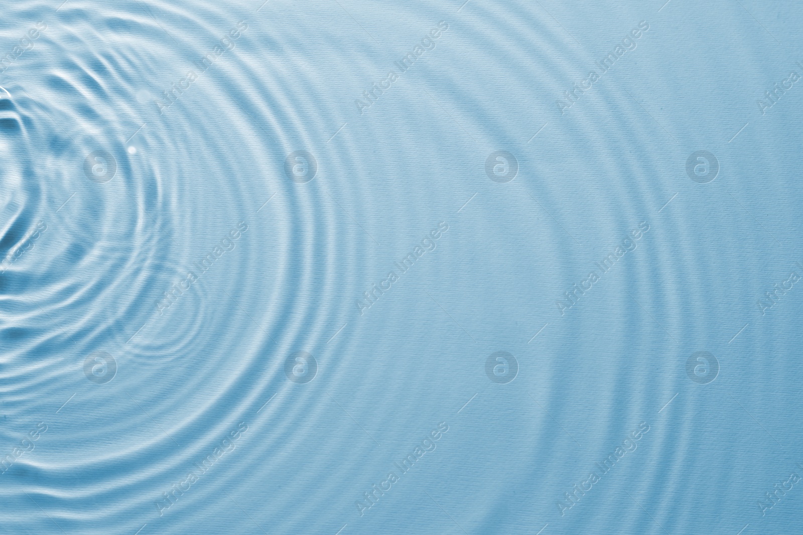 Image of Rippled surface of clear water on light blue background, top view