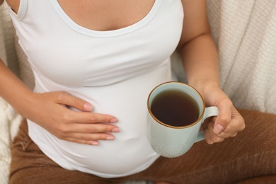 Photo of Pregnant woman drinking tea at home, closeup