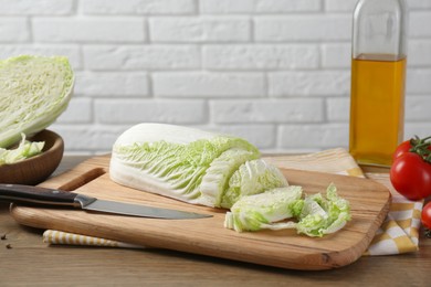 Photo of Cut fresh Chinese cabbage and knife on wooden table