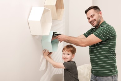 Father and son installing shelves on wall indoors. Repair work