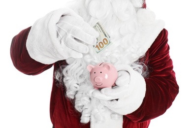 Photo of Santa Claus putting dollar banknote into piggy bank on white background, closeup