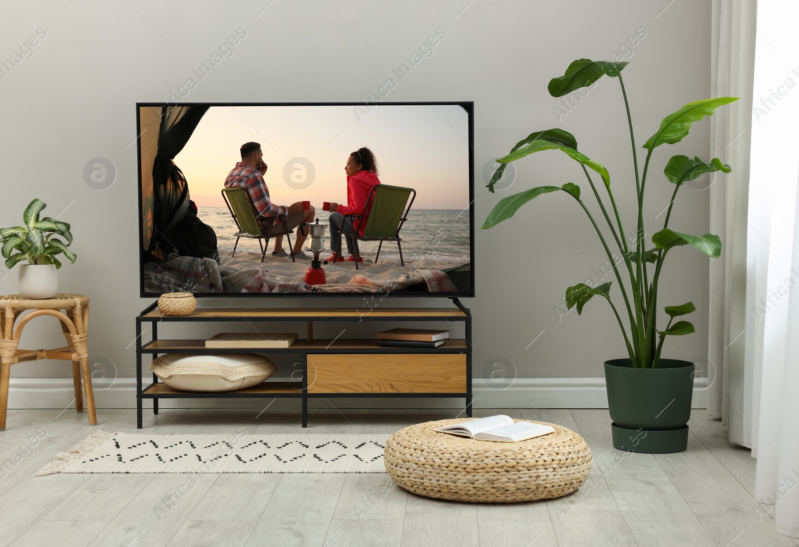 Image of Modern TV set on wooden stand in room. Scene of romantic movie on screen