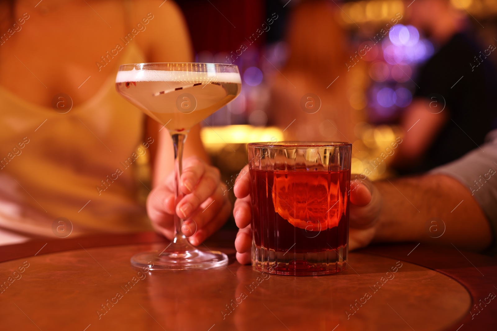 Photo of People with fresh cocktails at table in bar, closeup